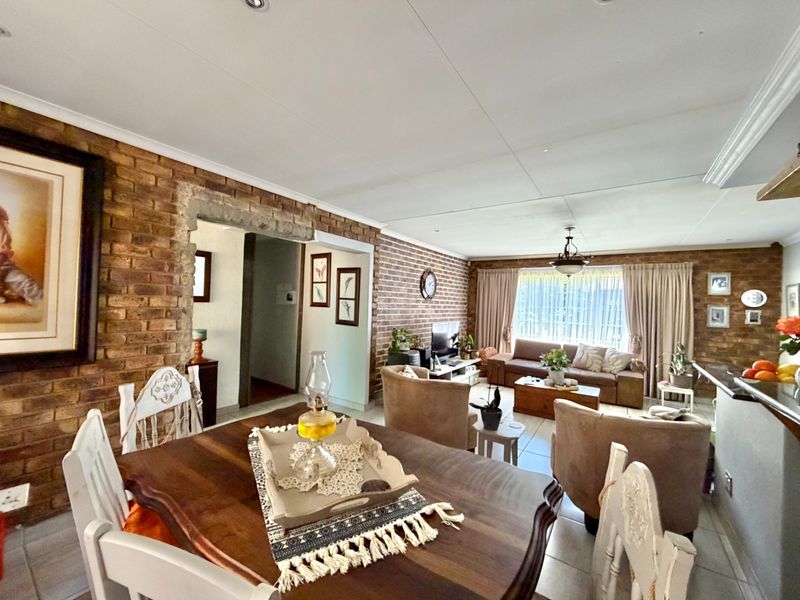 Spacious open-plan living and dining area featuring characterful exposed brick walls and tiled flooring, creating a warm and inviting atmosphere.