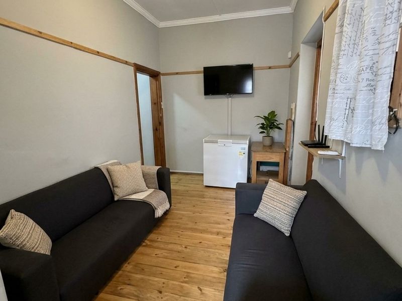 A living room featuring polished timber flooring, crown molding, and decorative timber wall trim, offering a functional and neutral space.