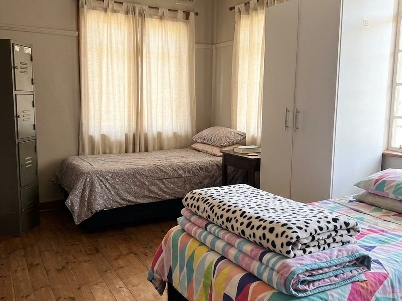 A bedroom featuring original timber flooring, picture rails, and dual windows allowing natural light.