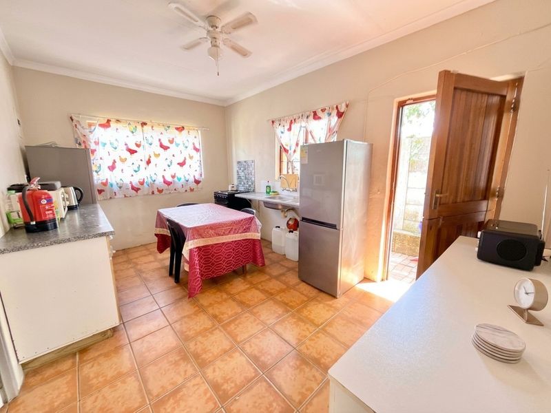 A functional kitchen featuring tiled flooring, a ceiling fan, and direct access to an outdoor area through a wooden door.