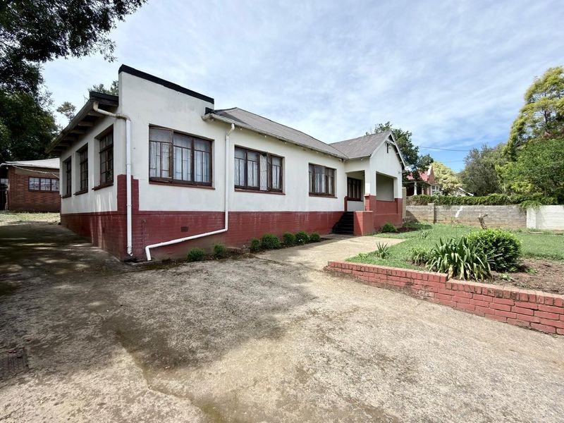 Front elevation of a single-story house featuring a concrete driveway, brick retaining wall, and covered entrance porch.
