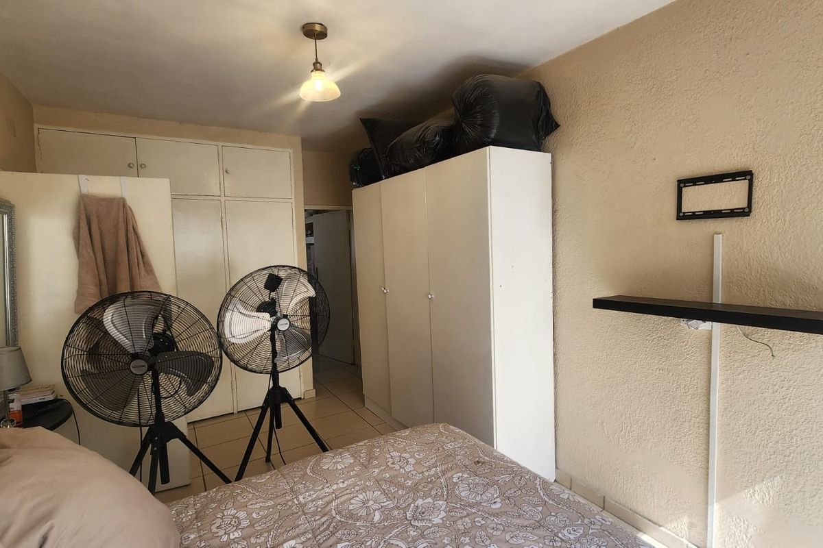 A bedroom featuring built-in cupboards and tiled flooring, offering a functional space with potential for cosmetic updates to enhance its overall appeal.