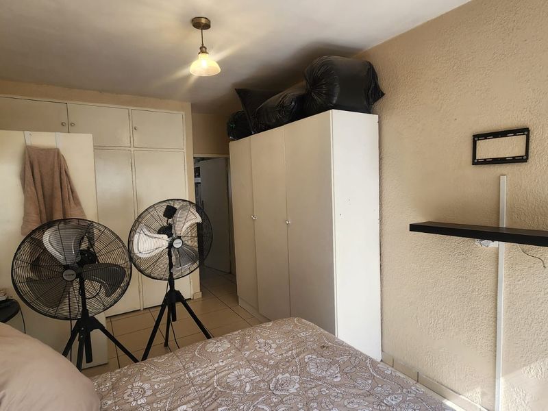 A bedroom featuring built-in cupboards and tiled flooring, offering a functional space with potential for cosmetic updates to enhance its overall appeal.