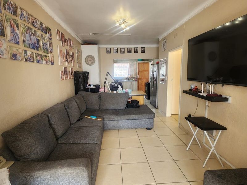 Open-plan living area featuring tiled flooring and a connected kitchen space, offering a functional layout for daily living.