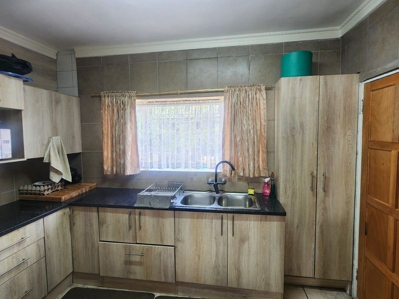 A functional kitchen featuring laminate cabinetry, granite countertops, a double basin sink, and tiled backsplash, offering a practical layout for daily use.