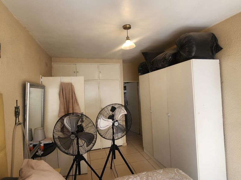 A bedroom featuring built-in cupboards and tiled flooring, providing functional storage space within the apartment.