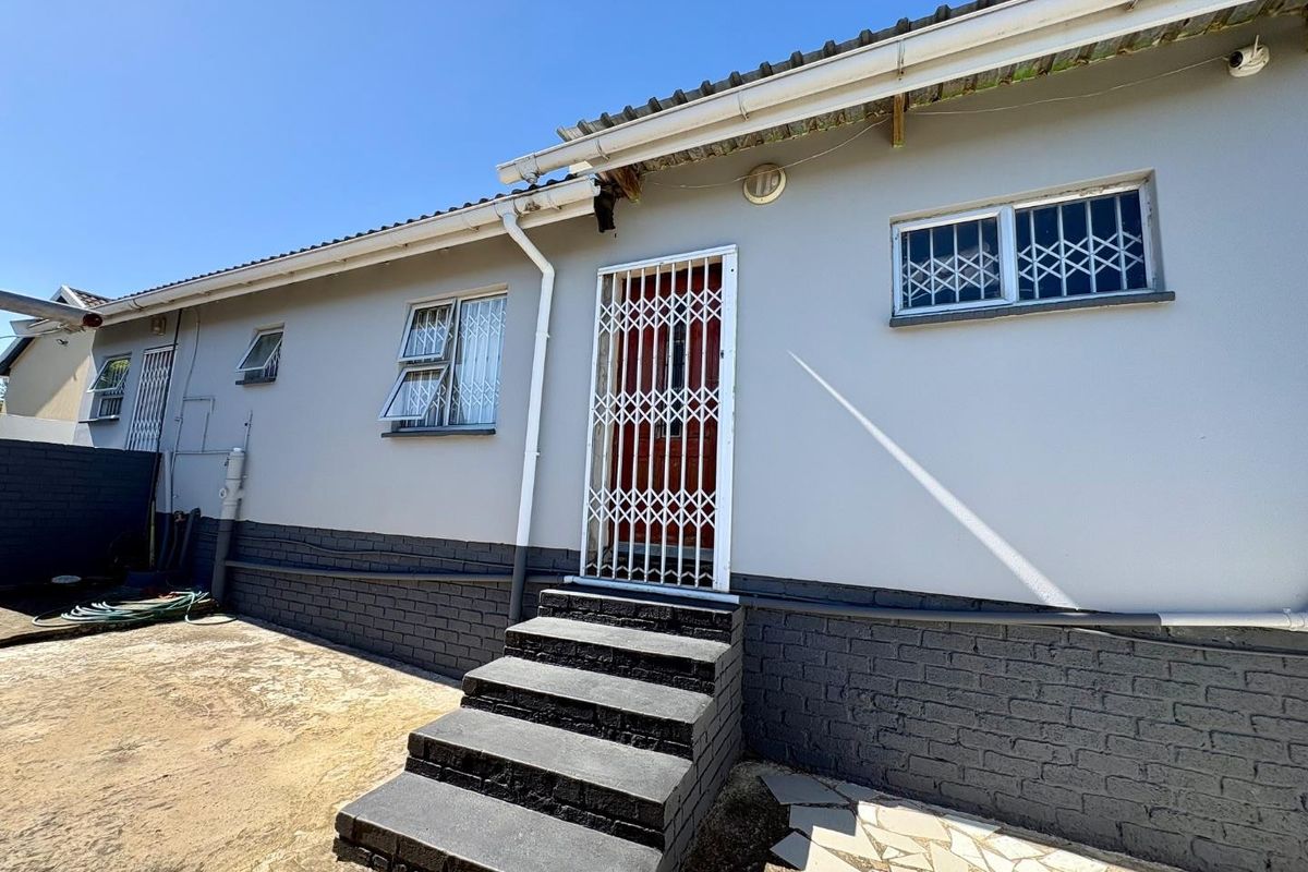 Rear exterior view of the house featuring a set of concrete steps leading to a security gate, with security bars on windows.