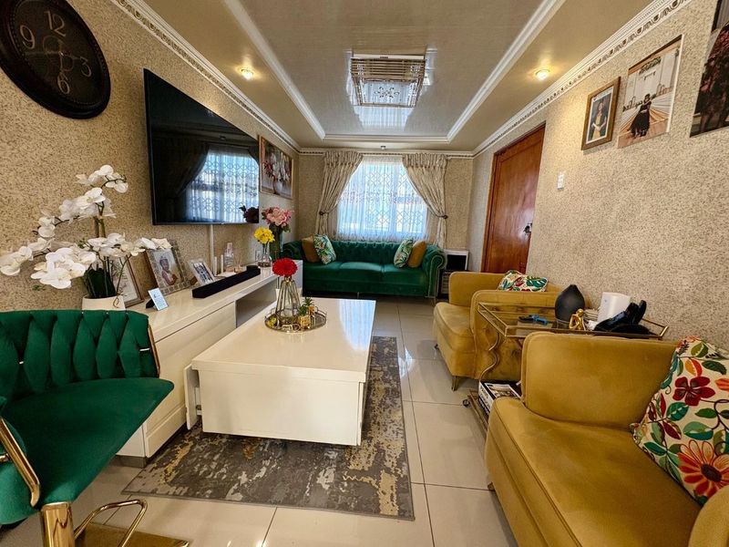 A well-maintained living room featuring tiled flooring, decorative ceiling cornicing, and recessed lighting, creating a comfortable and inviting atmosphere.