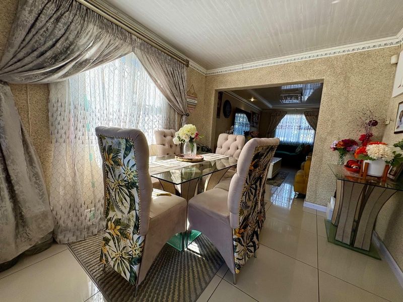A dining area featuring tiled flooring, decorative ceiling cornices, and textured wallpaper, seamlessly connected to an adjacent living space.