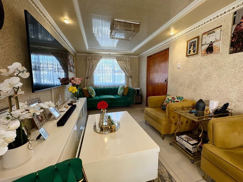 A well-maintained living room featuring textured wallpaper, decorative ceiling molding with recessed lighting, and glossy ceiling finishes.