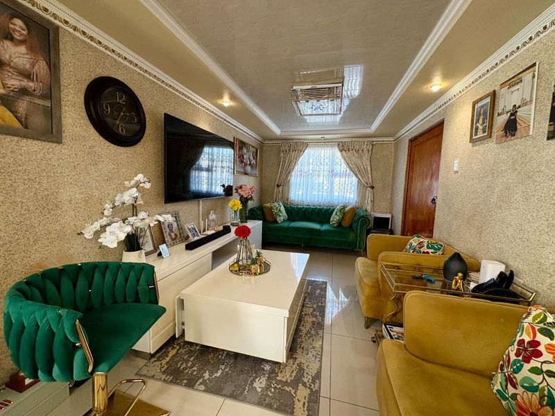 A well-maintained living room featuring tiled flooring, decorative ceiling cornicing, and recessed lighting, creating a comfortable and inviting space.