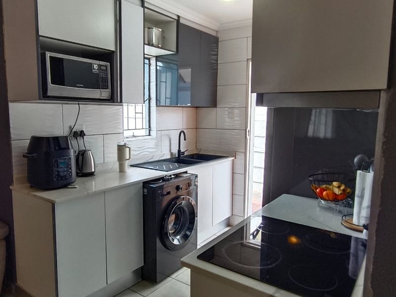 Modern kitchen featuring sleek cabinetry, stone countertops, integrated appliances, and a tiled splashback, offering a functional and contemporary cooking space.
