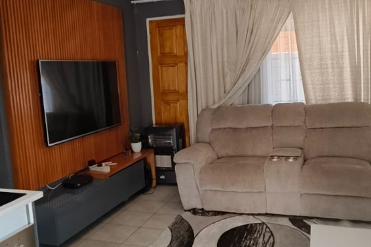 A living room featuring tiled flooring and a decorative wooden feature wall, providing a functional and comfortable space.