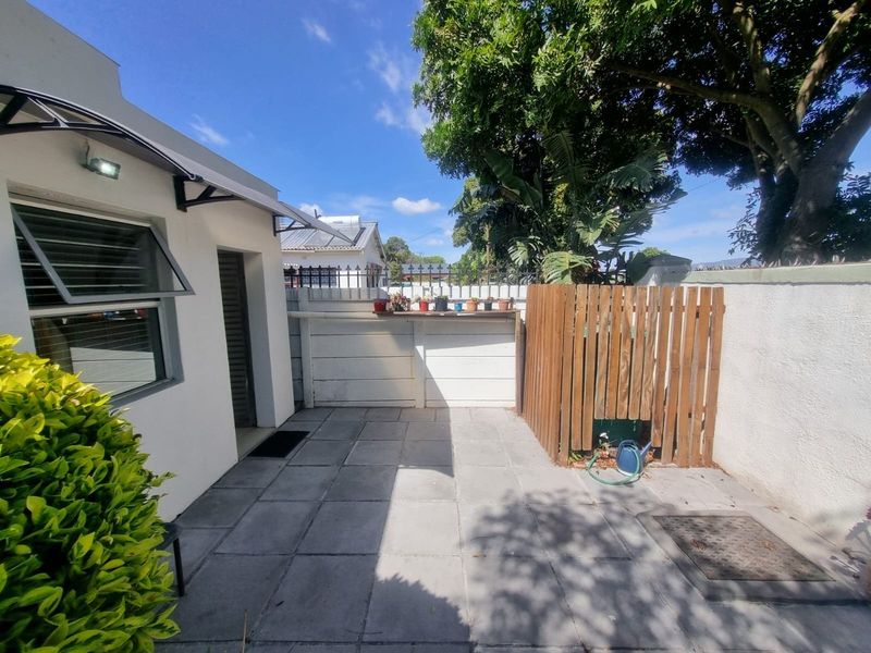 A neat rear courtyard featuring paved flooring, a timber privacy screen, and a functional awning over the exterior access point.