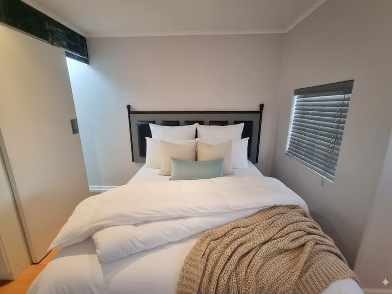 A cozy bedroom featuring neutral wall tones, a built-in wardrobe, and venetian blinds for adjustable natural light.