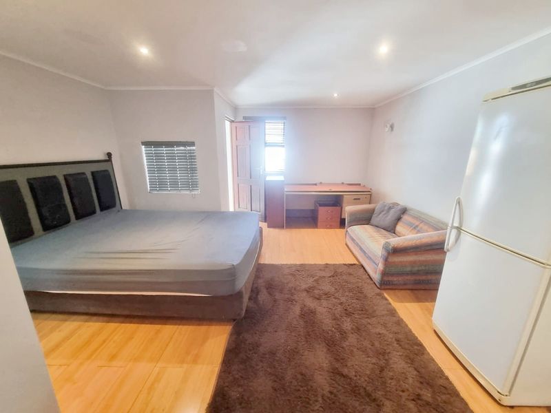 Spacious bedroom featuring laminate flooring, recessed downlighting, and natural light through a timber door and window with venetian blinds.