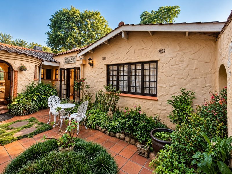 A charming rear courtyard featuring terracotta tiling, textured stucco walls, and established garden beds, providing a private outdoor living space.