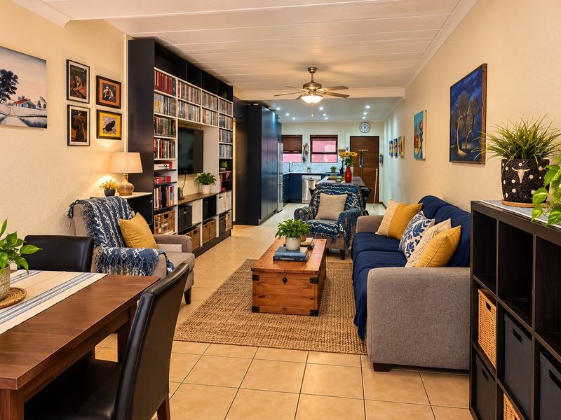 Spacious open-plan living and dining area featuring tiled flooring, a large built-in shelving unit, and a ceiling fan.
