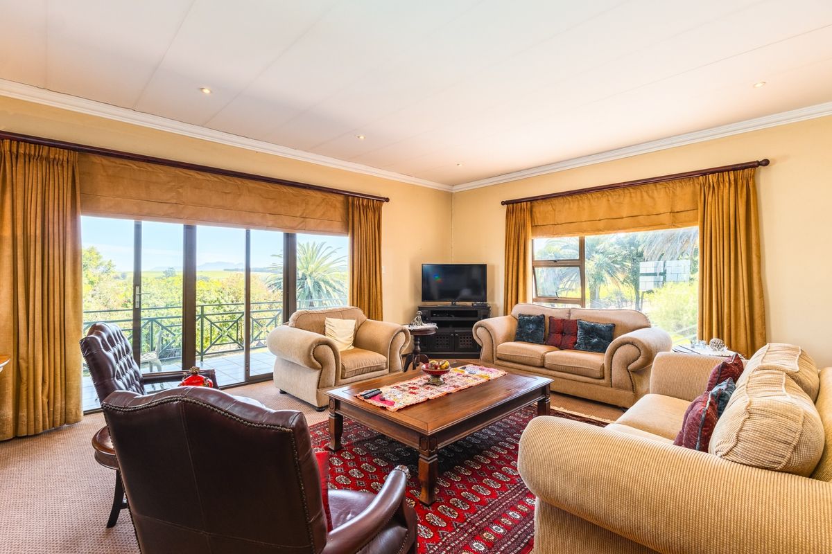 A spacious living room featuring large windows and sliding glass doors that provide ample natural light and access to an outdoor balcony area.