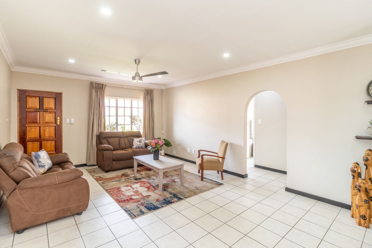 A bright living room featuring tiled flooring, a ceiling fan, recessed lighting, and an arched entryway leading to another area of the home.
