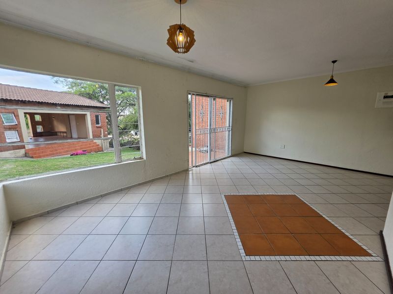 Spacious, light-filled living area featuring neutral tiled flooring, large windows, and direct access to the outdoor patio area.
