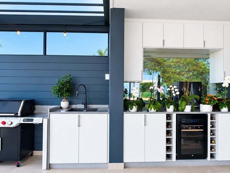Modern covered outdoor entertainment area featuring built-in cabinetry, stone countertops, a sink, and an integrated wine cooler under a stylish pergola roof.
