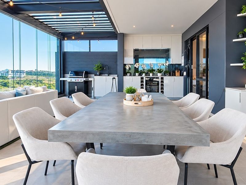 Spacious covered balcony featuring a modern built-in kitchenette, glass enclosure, and panoramic views, perfect for outdoor dining and entertaining.