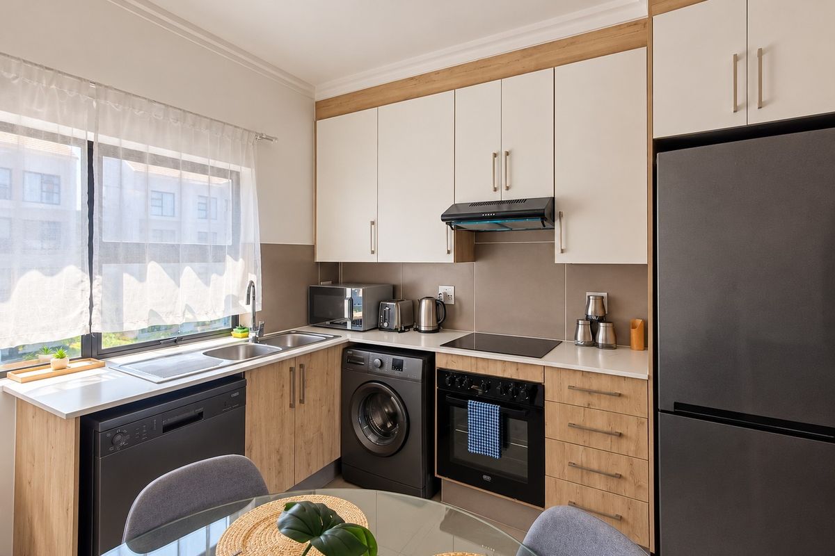 Modern kitchen featuring two-tone cabinetry, stone countertops, integrated dishwasher, built-in oven with hob, and a tiled splashback.