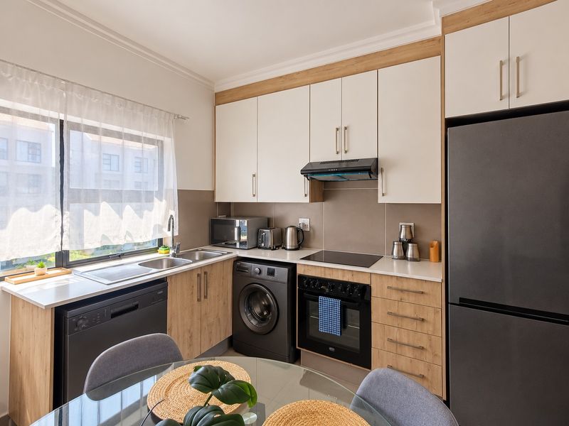 Modern kitchen featuring two-tone cabinetry, stone countertops, integrated dishwasher, built-in oven with hob, and a tiled splashback.