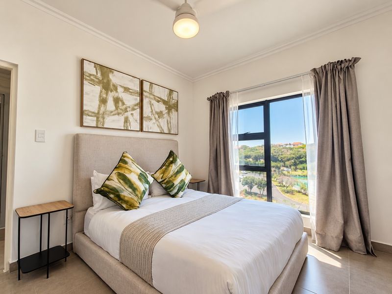 A well-maintained bedroom featuring tiled flooring, a ceiling fan, and a large window offering scenic outdoor views.