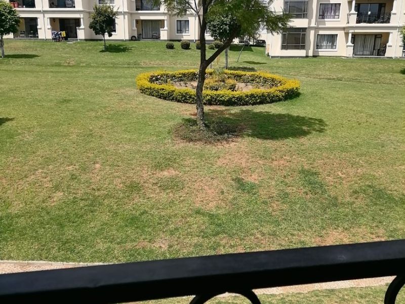 View from a balcony overlooking a well-maintained communal garden area between apartment blocks.