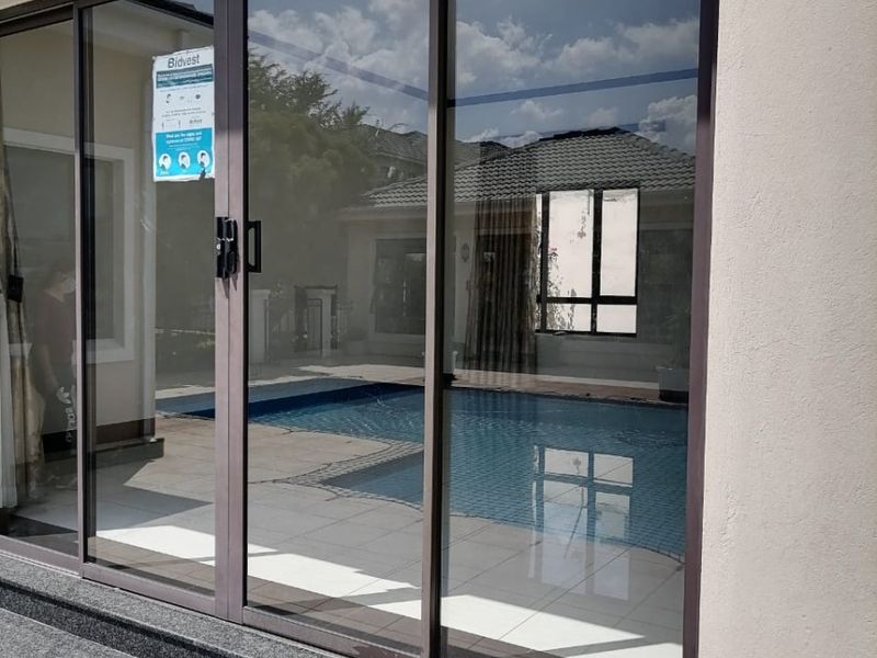 A covered patio area featuring dark-framed sliding glass doors and granite steps, providing a clear view of the adjacent swimming pool.