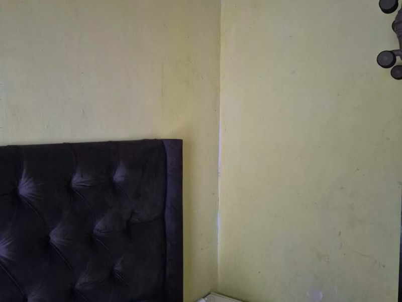 A bedroom corner showing significant ceiling water damage and wall surface deterioration, requiring maintenance and repair to restore the finish.