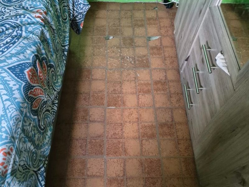 A bedroom interior featuring tiled flooring with visible damage and cracks, requiring maintenance or replacement.