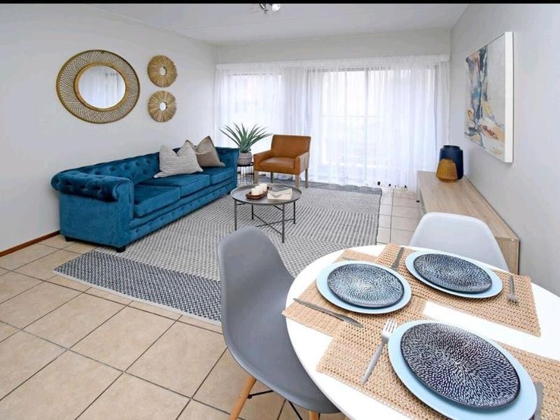 A bright open-plan living and dining area featuring neutral tiled flooring and large sliding glass doors that provide ample natural light.