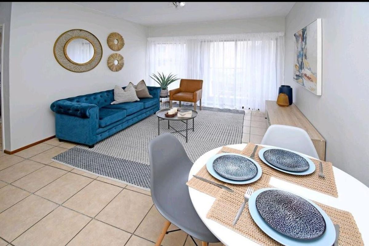 A bright open-plan living and dining area featuring neutral tiled flooring and large sliding glass doors that provide ample natural light.