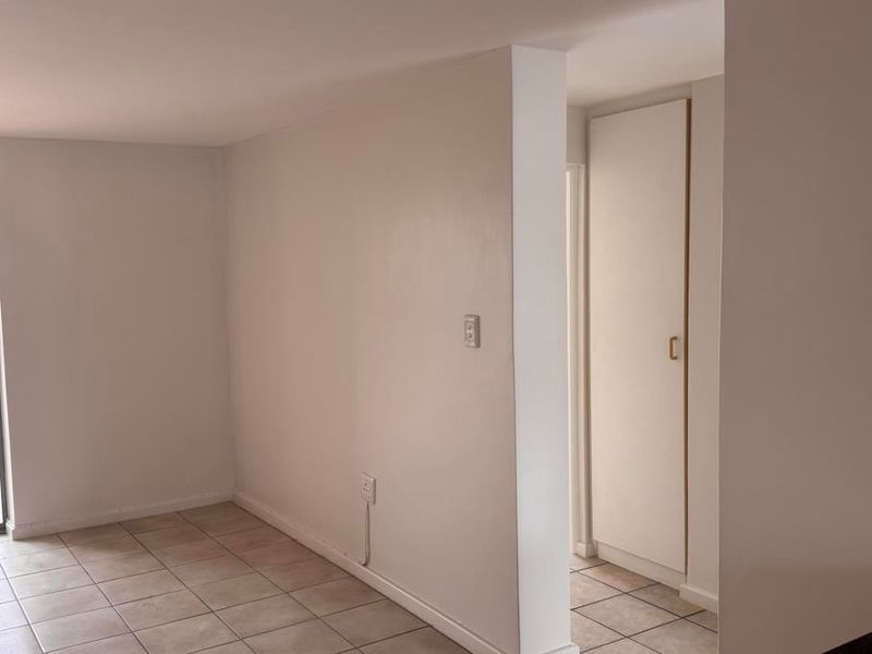 A clean, empty hallway featuring neutral tiled flooring and a built-in storage cupboard, providing a functional transition space within the apartment.