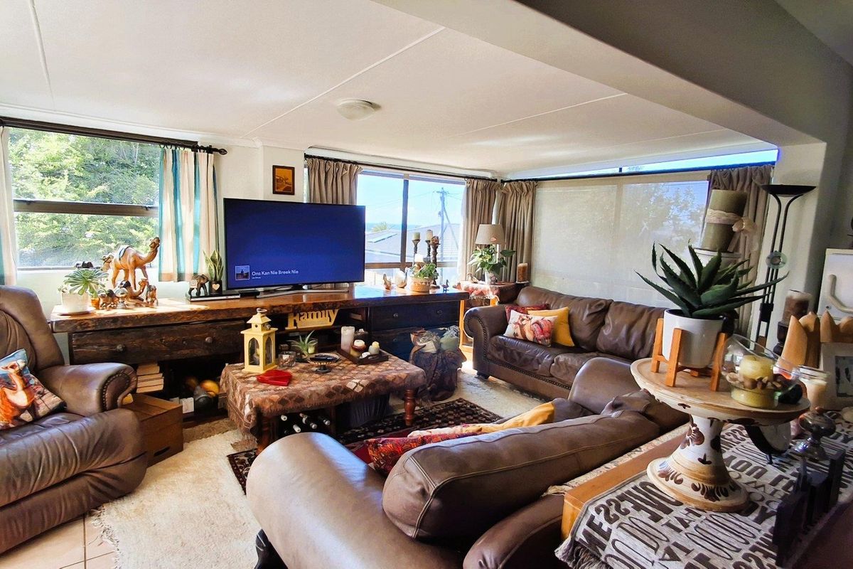 A spacious living room featuring large windows that provide ample natural light and tiled flooring throughout.