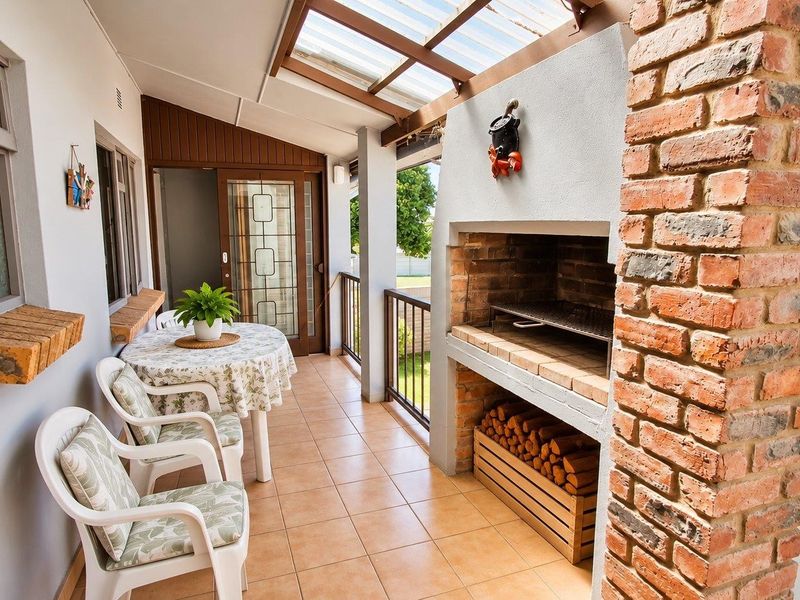 Covered patio featuring a built-in brick braai, tiled flooring, and a translucent roof, providing an ideal space for outdoor entertaining.