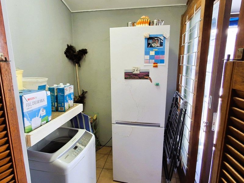 A functional laundry area featuring tiled flooring, built-in shelving, and wooden louvered doors providing access to the space.