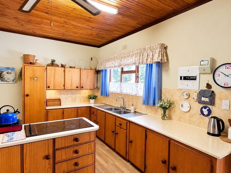 A functional kitchen featuring traditional wooden cabinetry, laminate countertops, a double basin sink, and a distinctive timber ceiling, offering a classic, lived-in aesthetic.