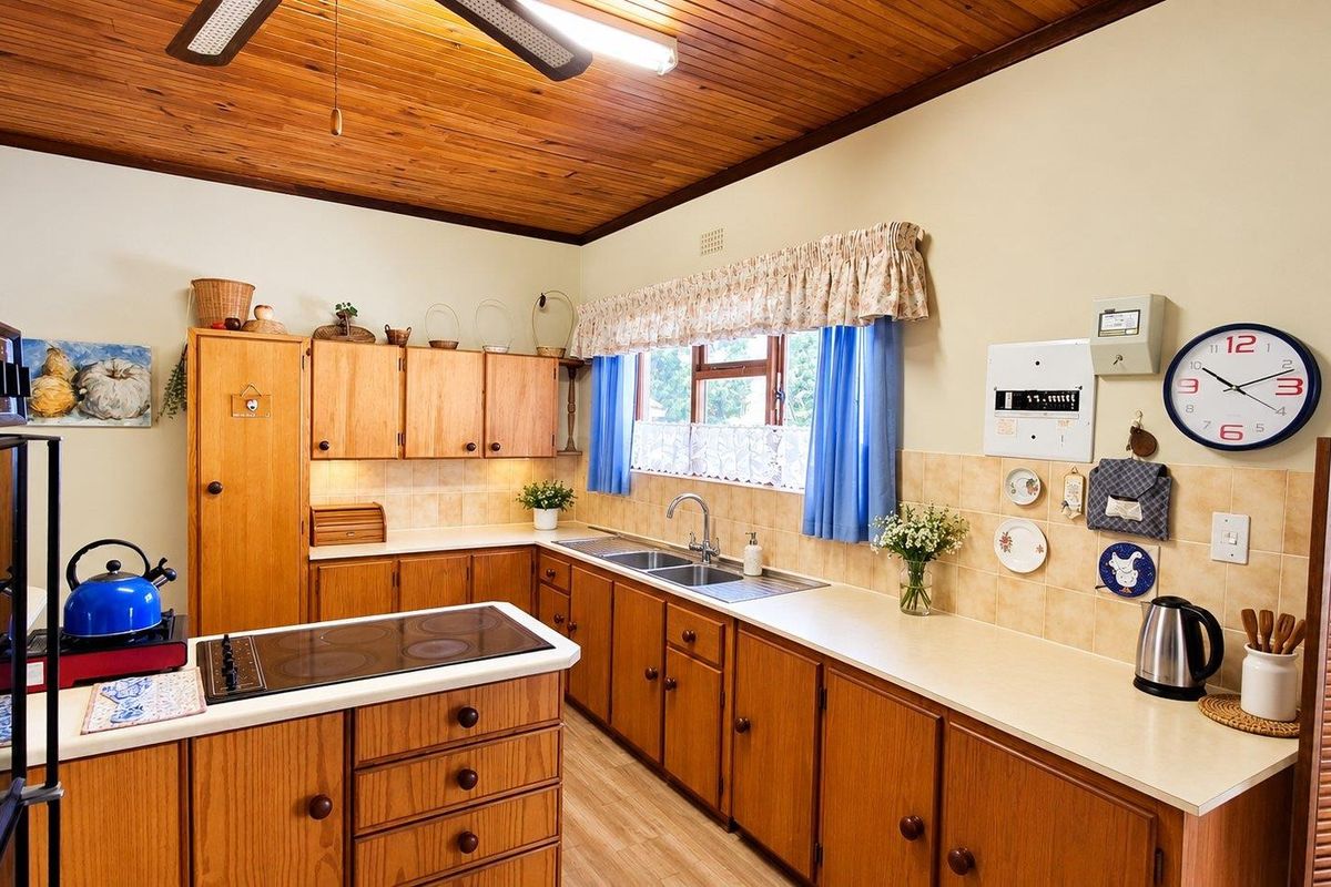 A functional kitchen featuring traditional wooden cabinetry, laminate countertops, a double basin sink, and a distinctive timber ceiling, offering a classic, lived-in aesthetic.