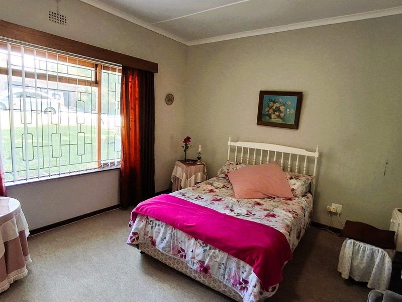 A standard bedroom featuring carpeted flooring, a large window with security bars, and coved ceiling detailing.