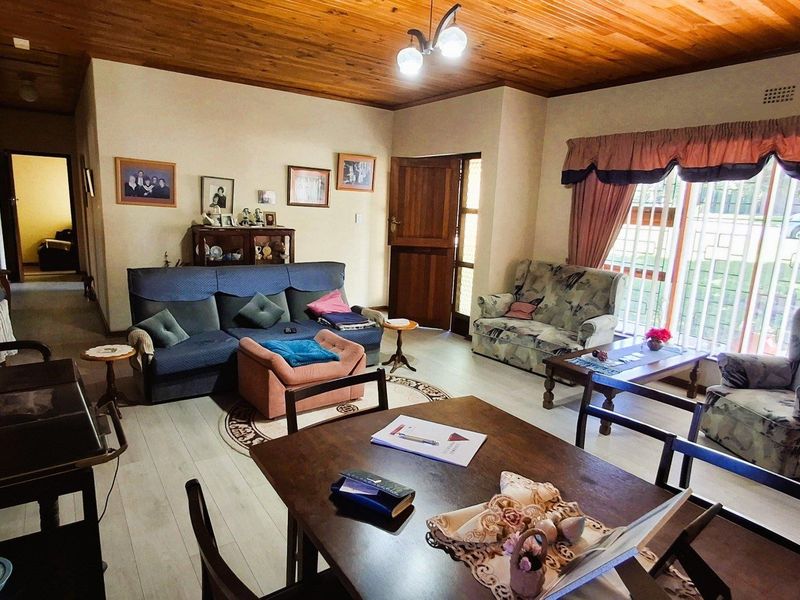 Open plan living and dining area featuring a timber ceiling, laminate flooring, and a large sliding glass door with security gate.