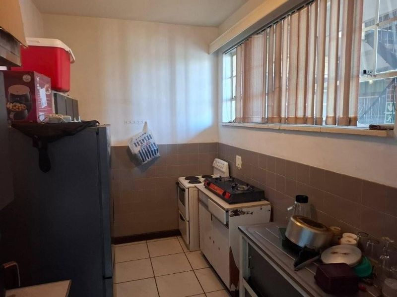 A functional kitchen featuring tiled flooring, a tiled splashback, and built-in cooking appliances, offering potential for modernization and cosmetic updates.