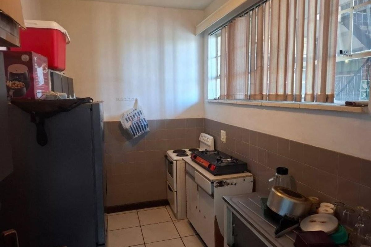 A functional kitchen featuring tiled flooring, a tiled splashback, and built-in cooking appliances, offering potential for modernization and cosmetic updates.