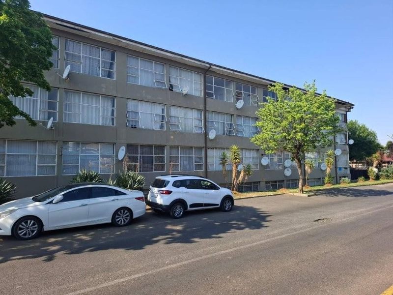 Exterior view of a multi-story apartment building facade featuring large window banks and multiple satellite dishes installed along the exterior walls.
