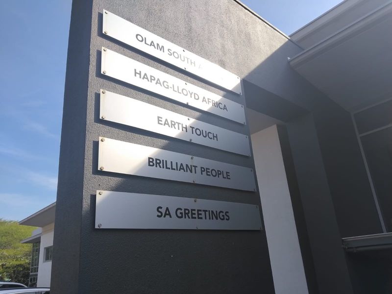 A modern office building exterior featuring a prominent tenant signage board mounted on a dark textured facade.