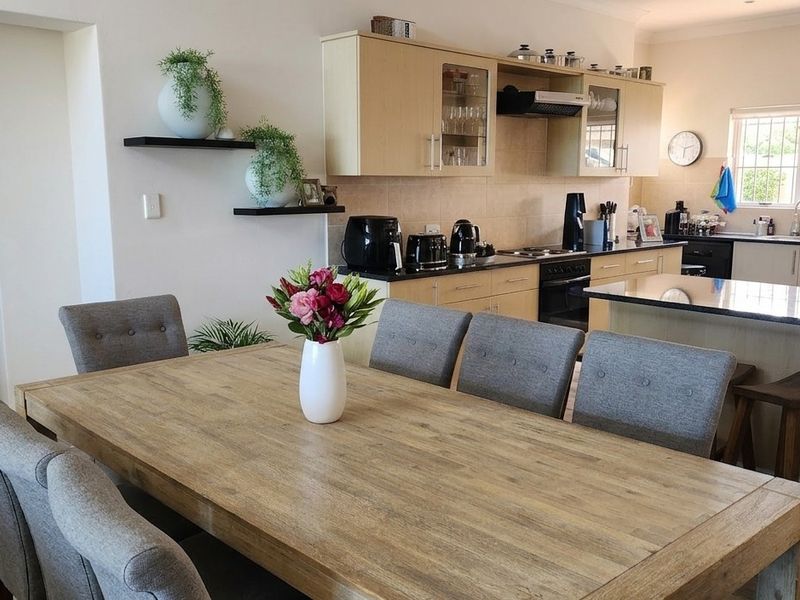 Open plan kitchen and dining area featuring light wood cabinetry, granite countertops, and modern laminate flooring, creating a functional and cohesive living space.