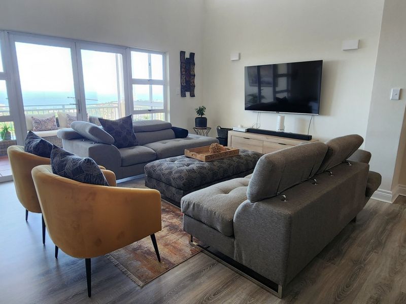 Spacious living room featuring high ceilings, modern laminate flooring, and large glass sliding doors that provide abundant natural light and access to the balcony.